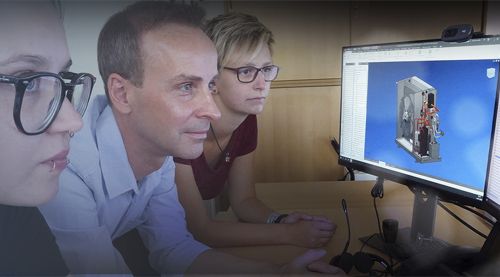Development engineers look together at two screens on a desk.