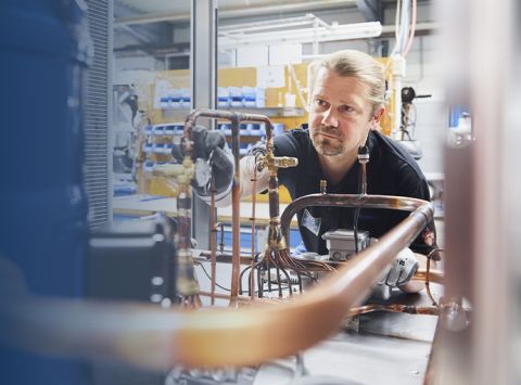 An employee of Glen Dimplex Precisioon Kooling works on the technical inner workings of a chiller.