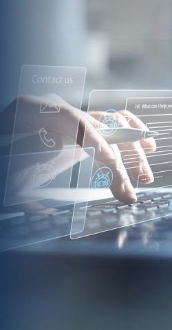 Zwei Hände die auf einer Laptop-Tastatur schreiben, ein Kugelschreiber zwischen den Fingern einer Hand. Ein Kontaktformular wird ausgefüllt.
