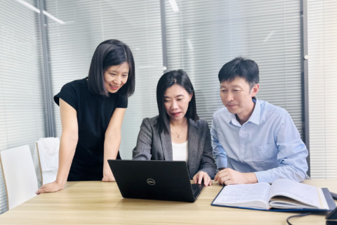 Three colleagues from Glen Dimplex China look at a laptop and work together.