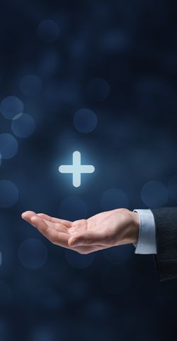 A picture with a graphic dark gray-blue background. An outstretched arm holds a plus sign hovering above it as a symbol of added value & service.